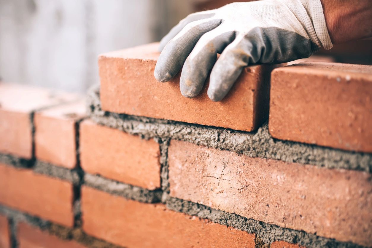 A person in gloves is building a brick wall.
