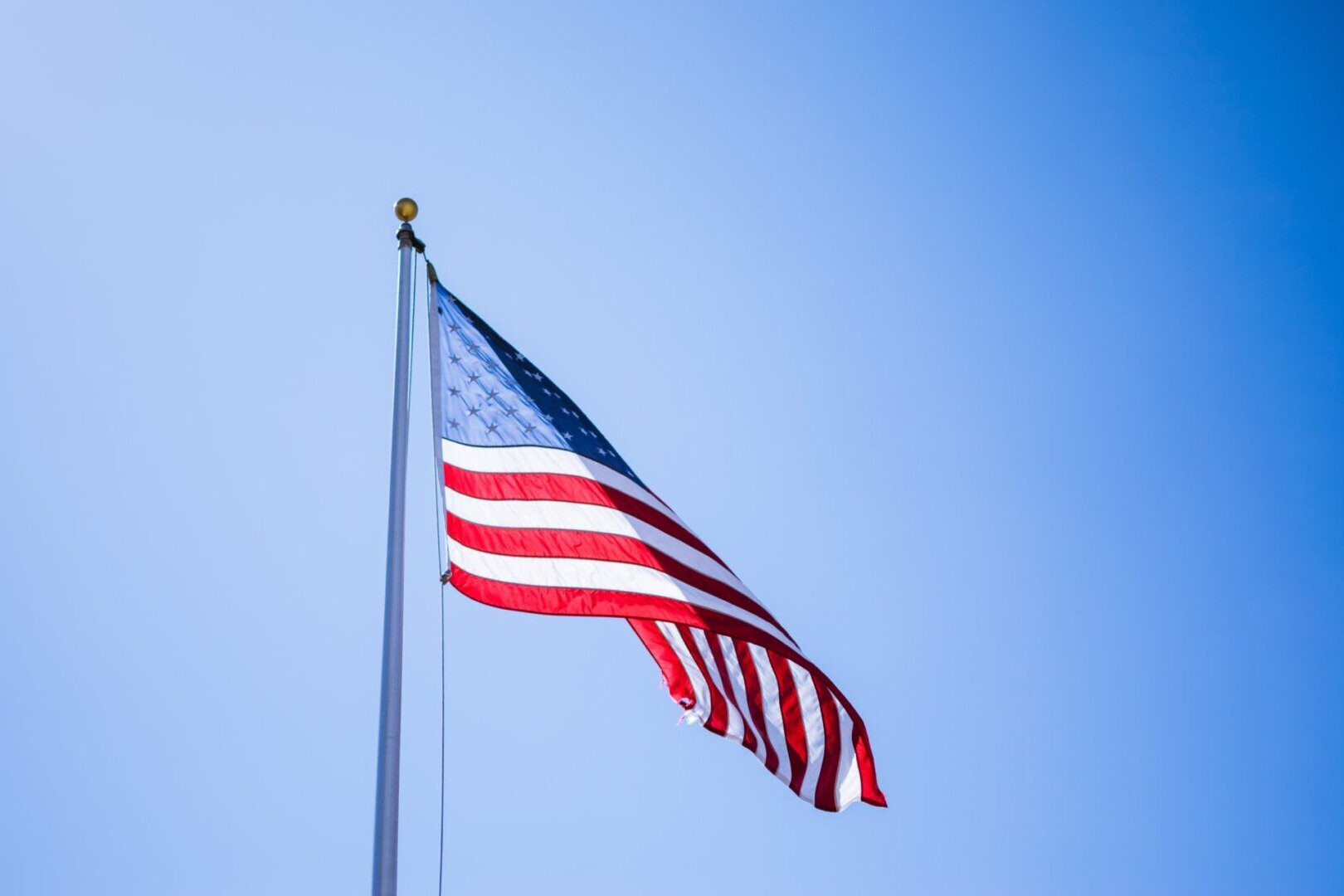 A Flying American Flag With a Sky Color Background